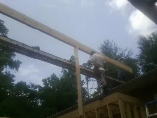 Carpenter setting a ridge beam over a new addition frame — Ice Dam Removal by Roofing Brothers in Metz