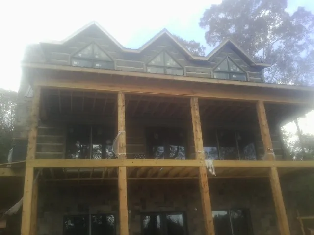 Dormers and porch framing on a large log home under construction — Roof Coating work by our crew in Metz