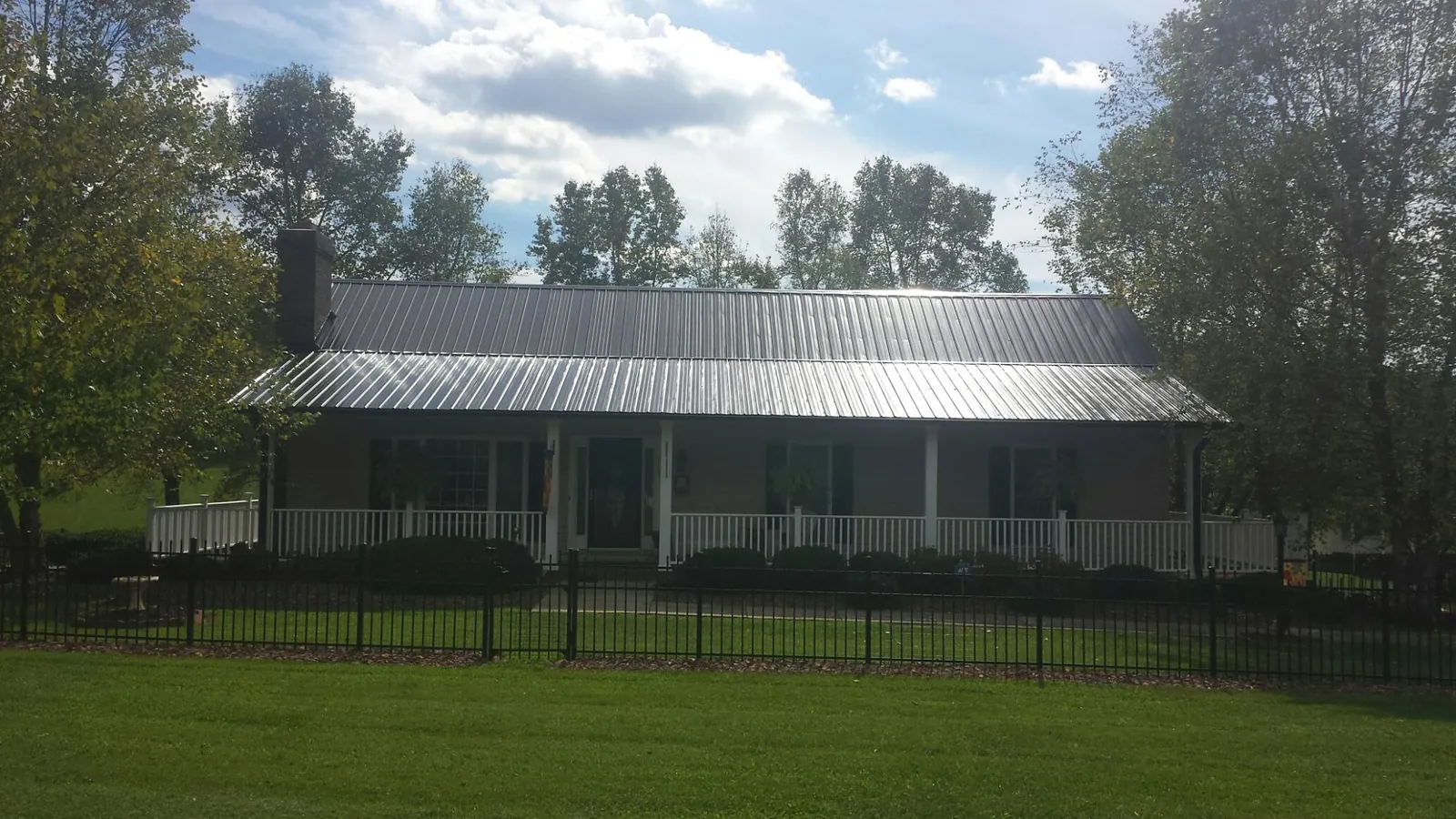 Gray metal roof on a brick ranch with a full width front porch — Gutter Guard Installation work by our crew in Metz