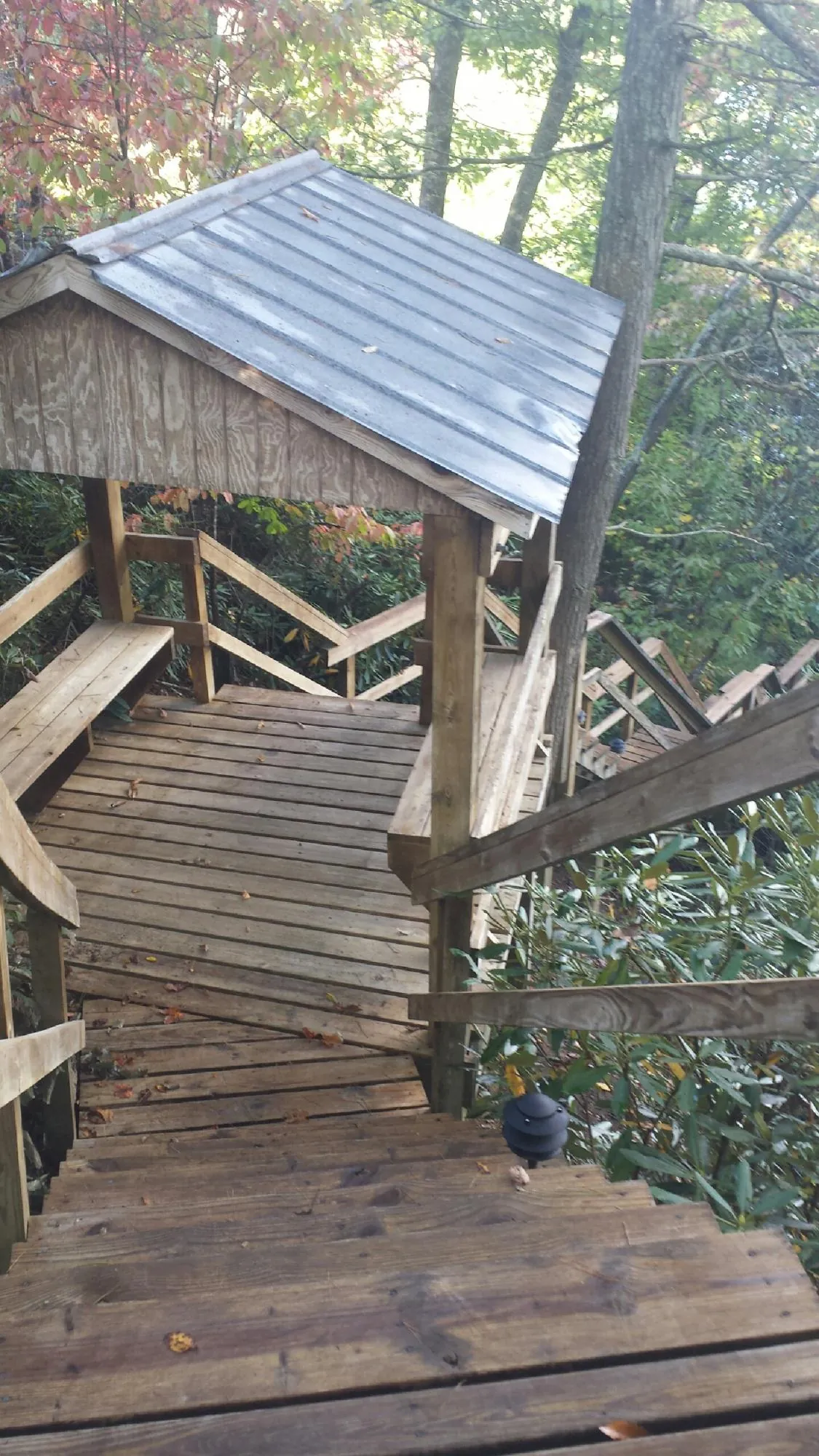 Metal roofed shelter over wooden steps on a wooded walkway — Skylight Repair & Installation work by our crew in Metz