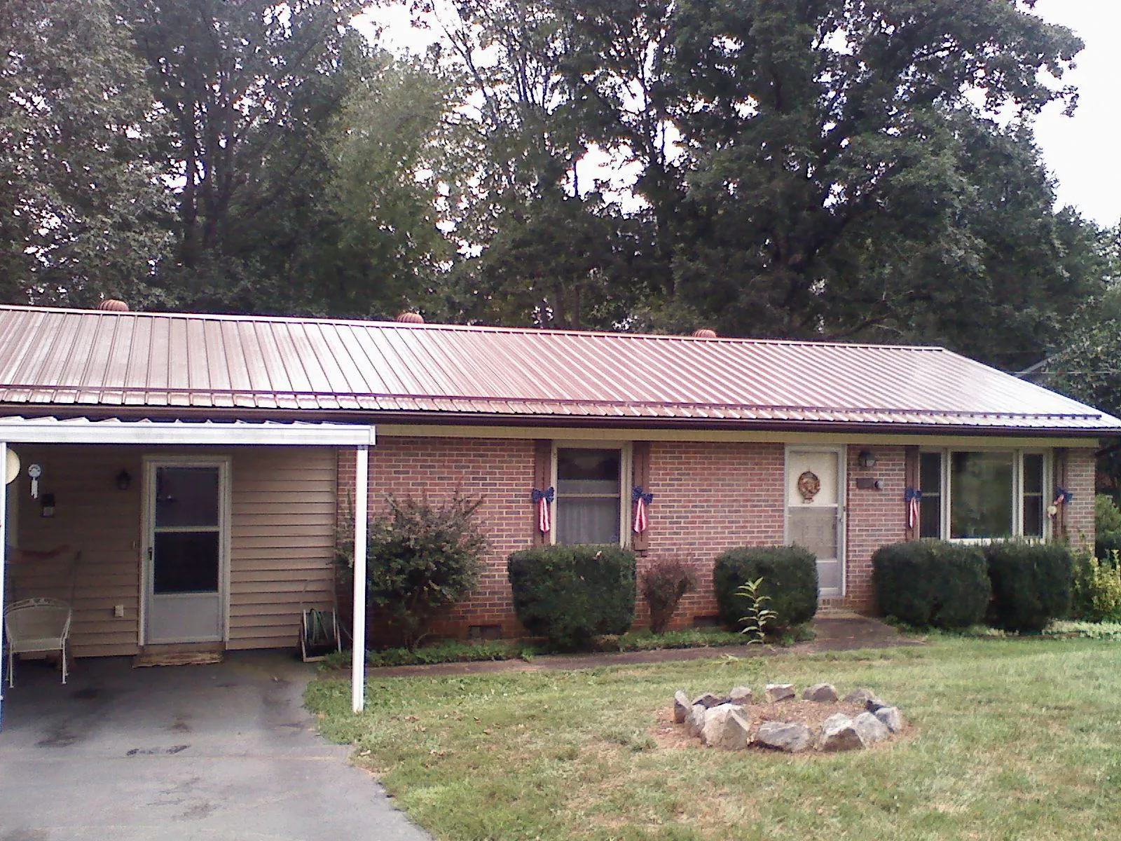 Bronze metal roof and carport on a brick ranch home — Roof Repair work by our crew in Metz