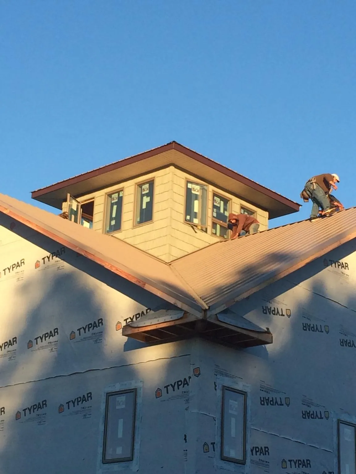 Roofers working around a rooftop cupola on a new metal roof at sunset — Roof Waterproofing in Metz by Roofing Brothers